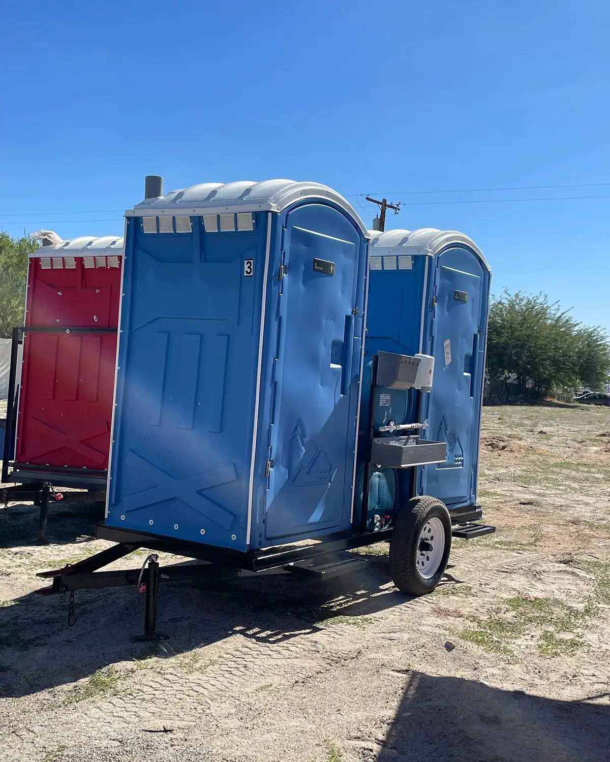 Truck hauling a trailer loaded with portable toilets arriving at a job site for delivery