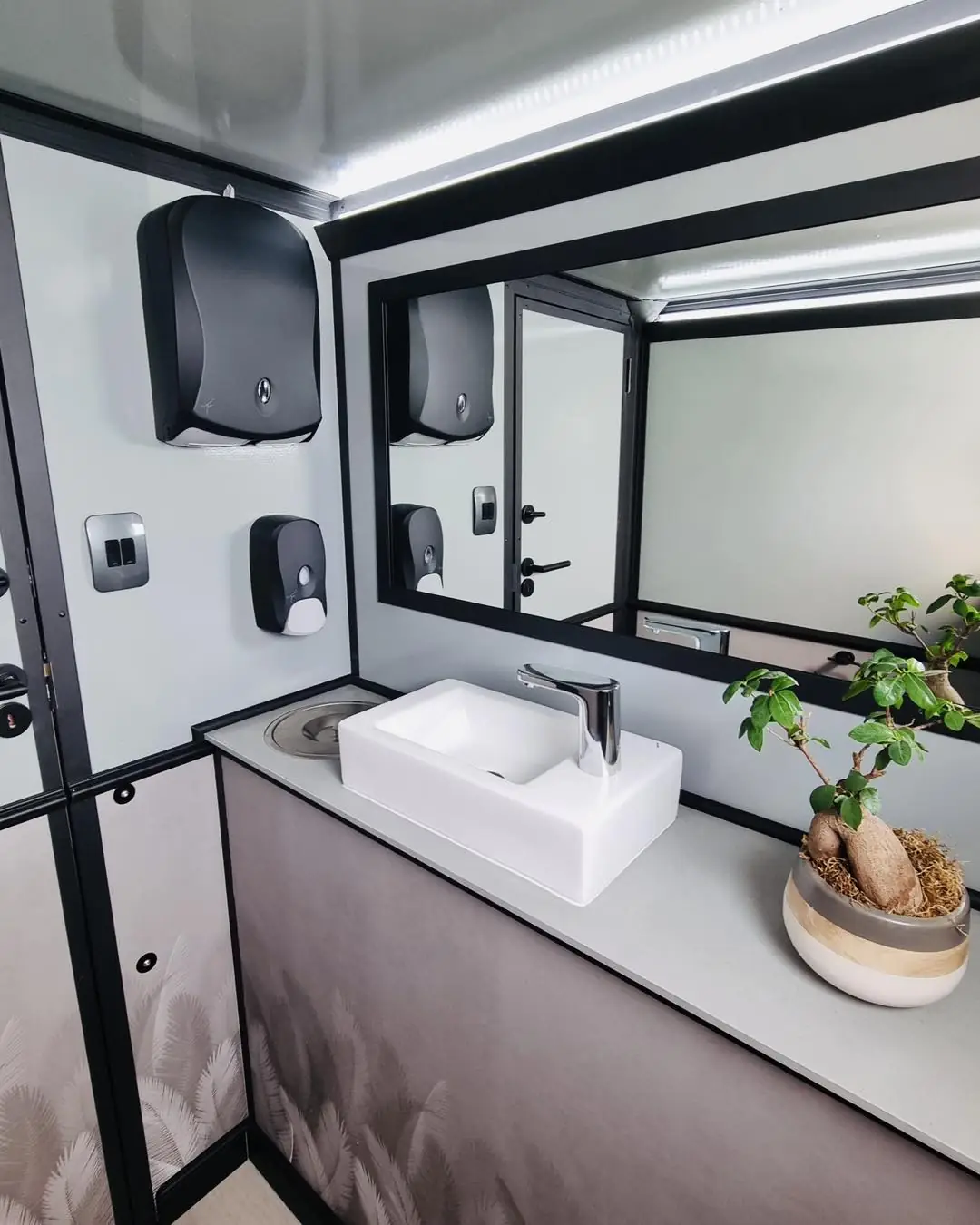 Restroom trailer interior with vanity, mirror, soap and towel dispensers