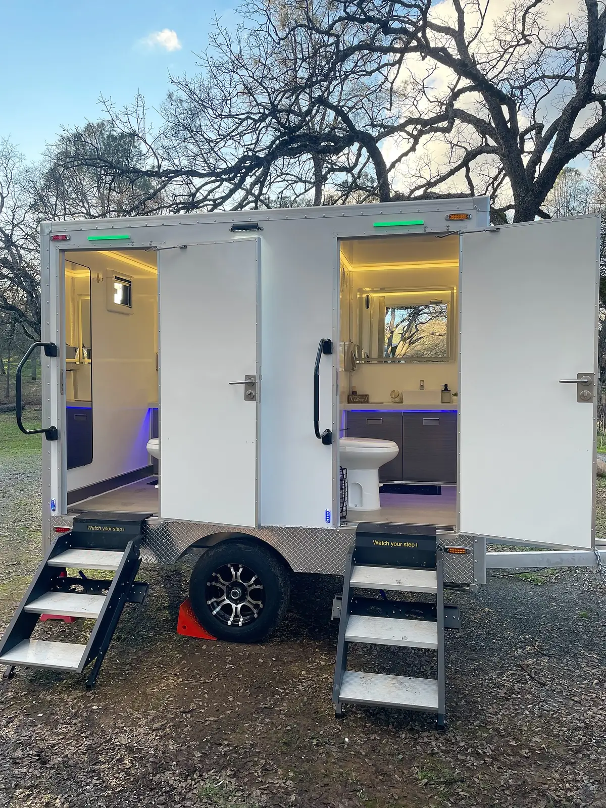 Two-room trailer with steps set up outdoors at dusk