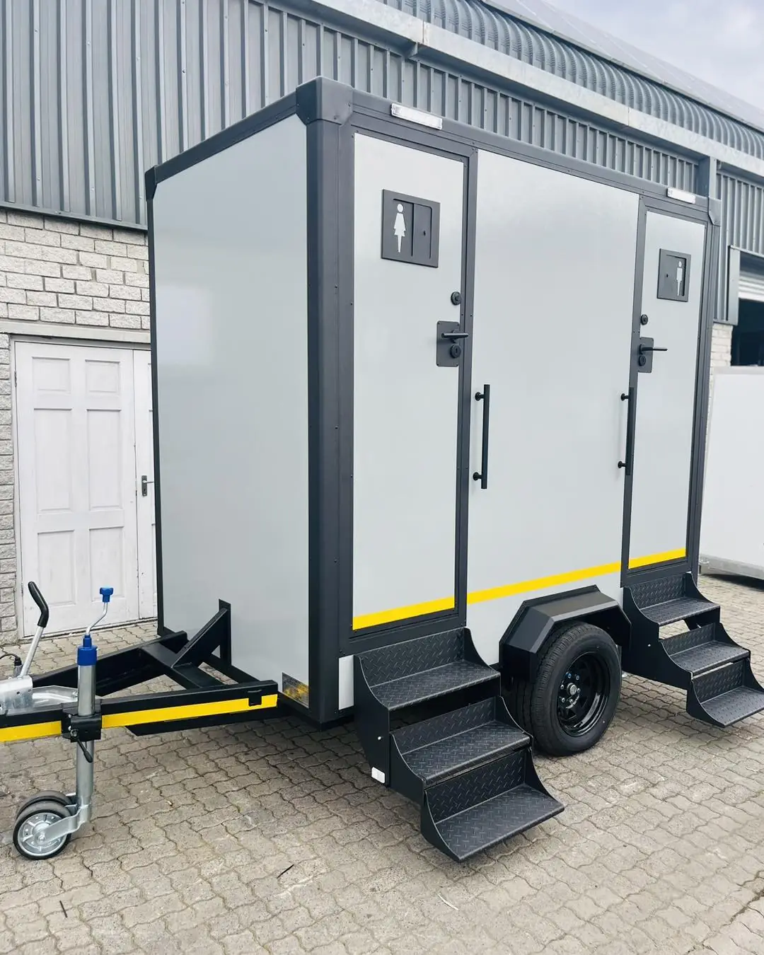 Two-stall restroom trailer with fold-down steps